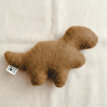 a simple stuffed figure in the shape of a dinosaur-shaped chicken nugget