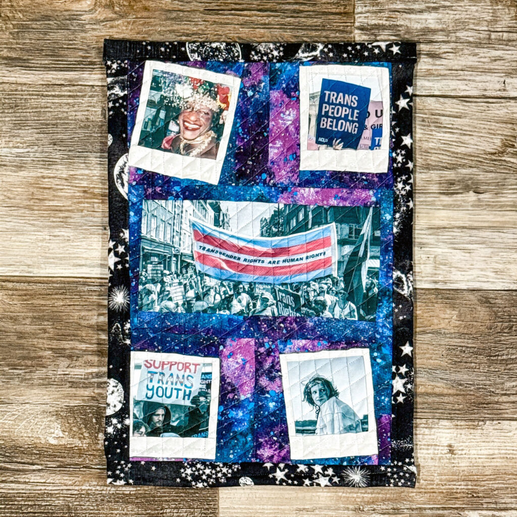 mixed media collage on black fabric with star and sunburst patterns, featuring polaroid-style photographs of protest imagery, trans rights signage, and activist moments layered with vibrant blue and magenta paint splashes